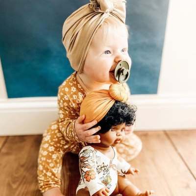 Bébé au bandana qui joue avec une poupée minikane